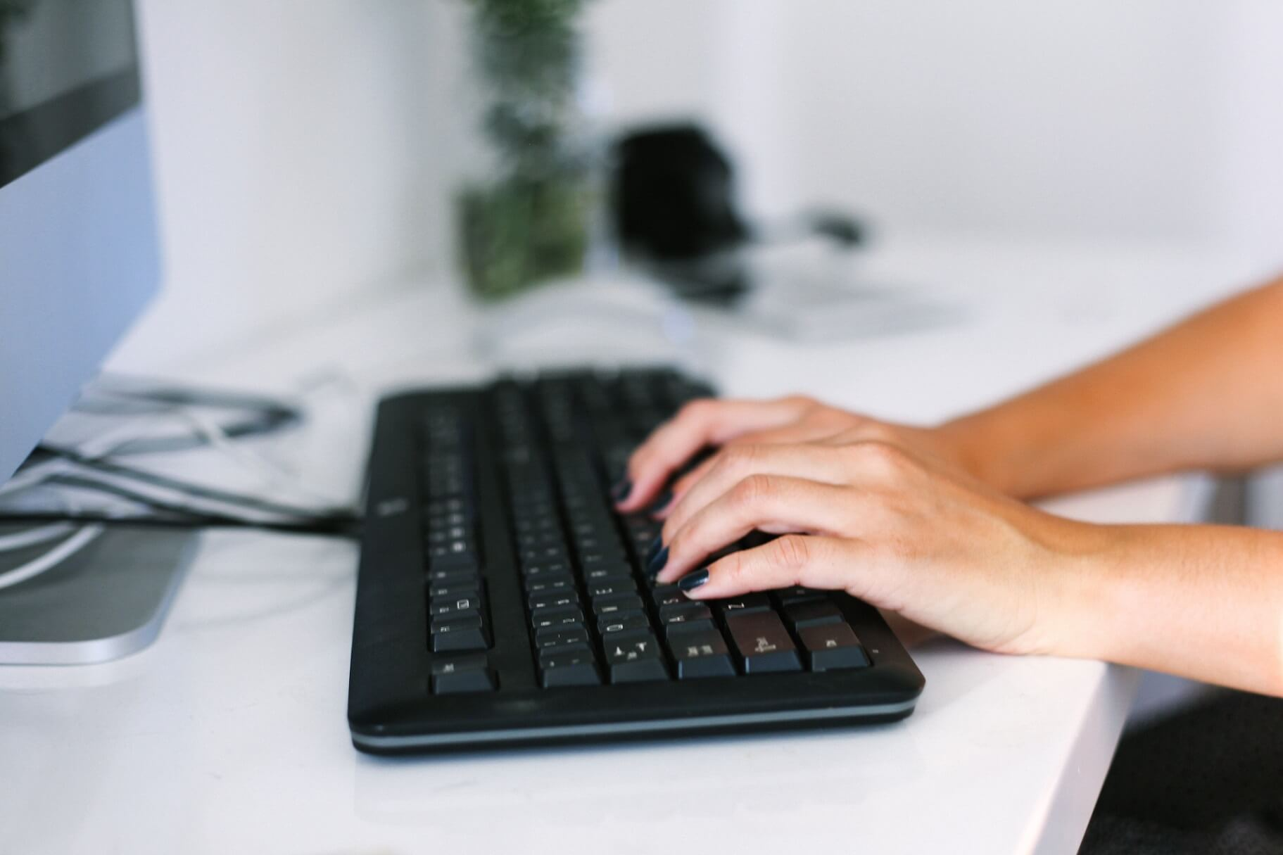 womans-hands-typing-on-keyboard-at-desk-working